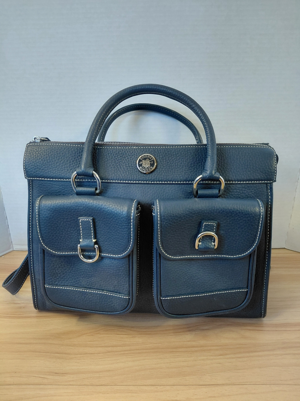 Dooney & Bourke Navy blue leather satchel with white stitching.